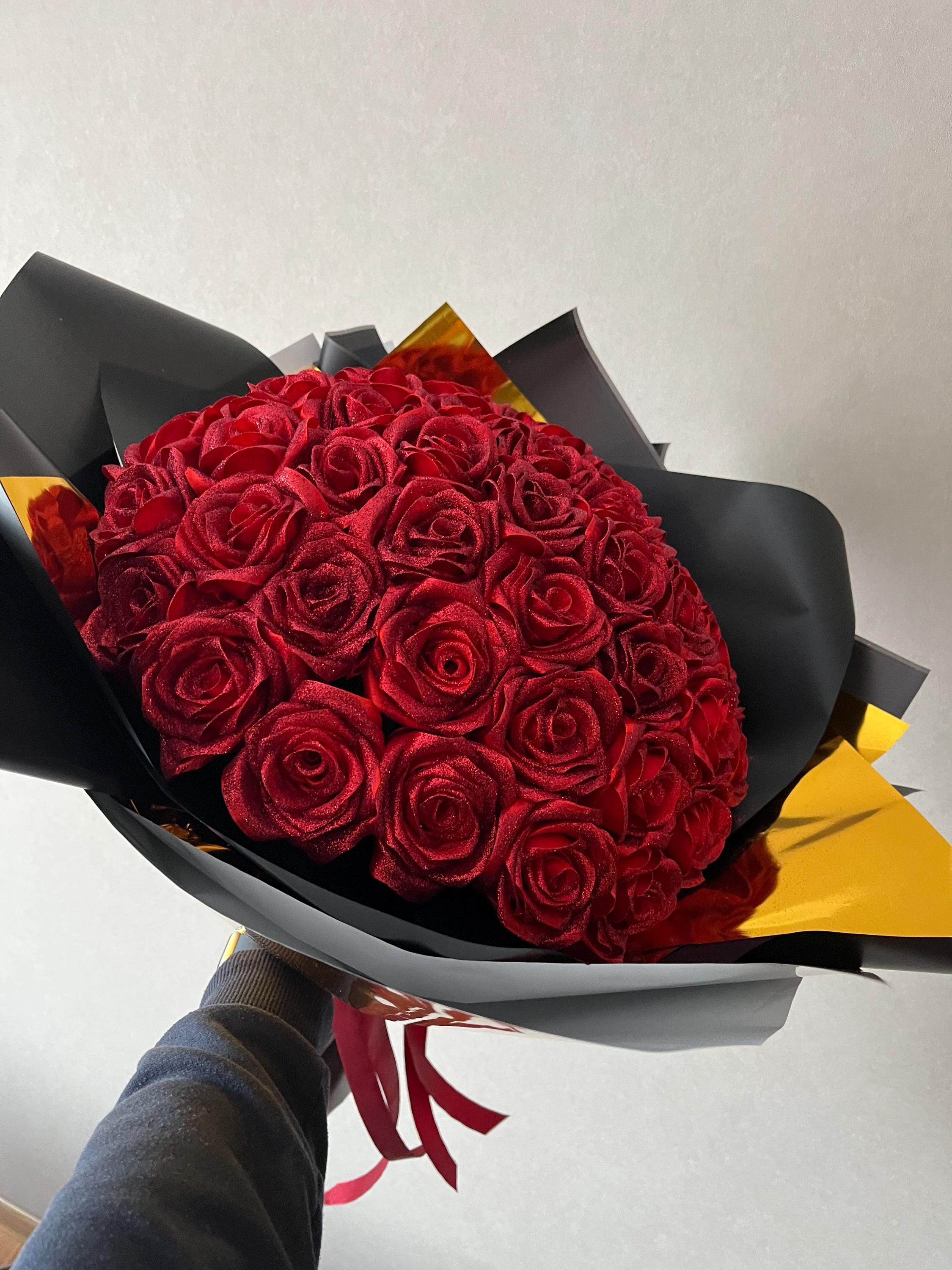ブラックゴールドのラッピングに入った赤いバラの花束、キラキラ輝く
