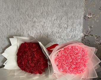 Può includere: Due mazzi di rose artificiali, uno rosso e uno rosa, avvolti in carta velina bianca e legati con un nastro.