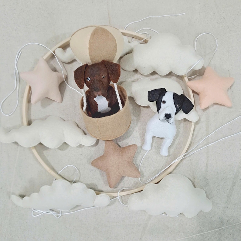 May include: A wooden mobile with felt clouds, stars, and dogs. One dog is in a hot air balloon, and the other is hanging below a cloud.