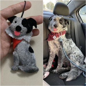 May include: A gray and black dog plush toy with a red bandana. The toy is sitting in a hand. The dog is wearing a red bandana with white polka dots.