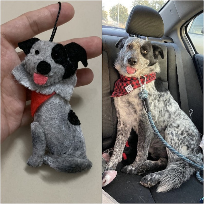 May include: A gray and black dog plush toy with a red bandana. The toy is sitting in a hand. The dog is wearing a red bandana with white polka dots.