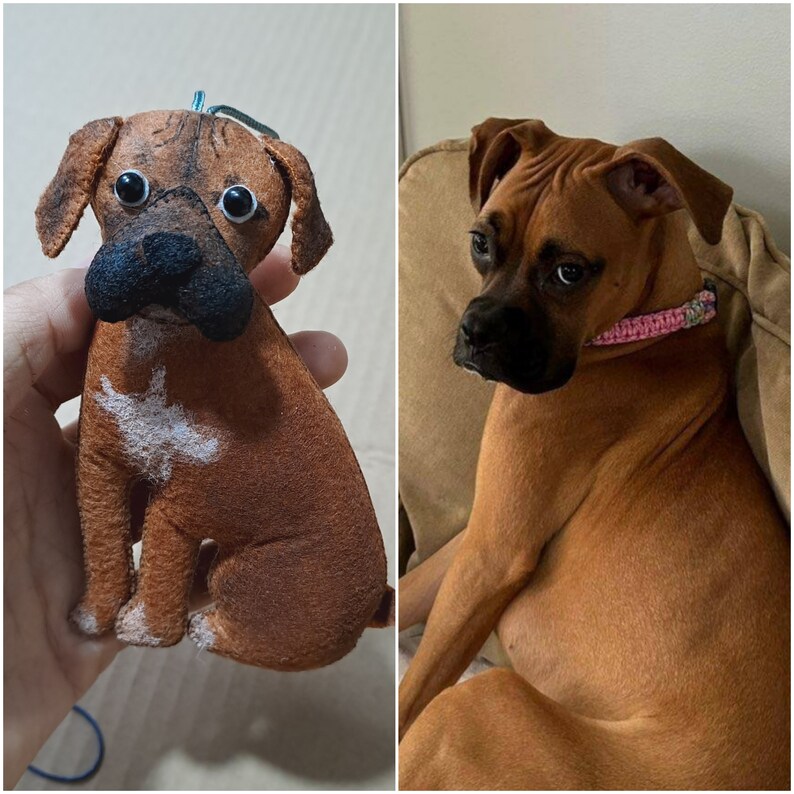 May include: A brown and white plush toy dog with big brown eyes. The toy is sitting on a hand.  Next to the toy is a real brown and white boxer dog sitting on a couch.