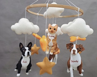 May include: A white, brown, and yellow baby mobile with a cat, two dogs, and clouds. The cat is named Sonny, one dog is named Gordy, and the other dog is named Zeli.