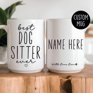 May include: Two white ceramic mugs with black text. One mug says "best dog sitter ever" with a small heart. The other mug says "NAME HERE" with the text "With Love, Lexi" and a paw print.
