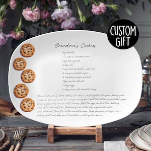 May include: White oval ceramic serving platter with a handwritten recipe for Grandma's Cookies. The recipe includes ingredients like all-purpose flour, baking soda, butter, sugar, vanilla extract, and chocolate chips. The platter has four chocolate chip cookies painted on it.