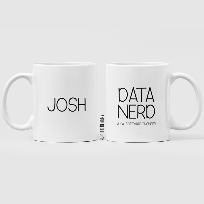 以下が含まれることがあります： 黒い文字が書かれた白いセラミック製のマグカップ2つ。左側のマグカップには「Josh」と書いてあり、右側のマグカップには「Data Nerd AKA Software Engineer」と書いてあります。