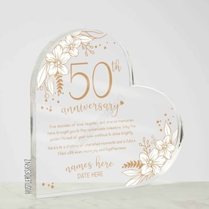 Puede incluir: Una placa acr&iacute;lica transparente en forma de coraz&oacute;n con dise&ntilde;os florales dorados y el texto "50 aniversario". La placa tambi&eacute;n incluye el texto "Cinco d&eacute;cadas de amor, risas y recuerdos compartidos te han llevado a este hito extraordinario. Que el hilo dorado de tu amor siga brillando. Brindo por una vida de momentos preciados y un futuro lleno de a&uacute;n m&aacute;s alegr&iacute;a y uni&oacute;n. nombres aqu&iacute; FECHA AQU&Iacute;".
