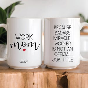 Könnte beinhalten: Zwei weiße Keramikbecher mit schwarzem Text. Ein Becher sagt "Work Mom" mit einem roten Herzen. Der andere Becher sagt "Weil Badass Miracle Worker kein offizieller Jobtitel ist".
