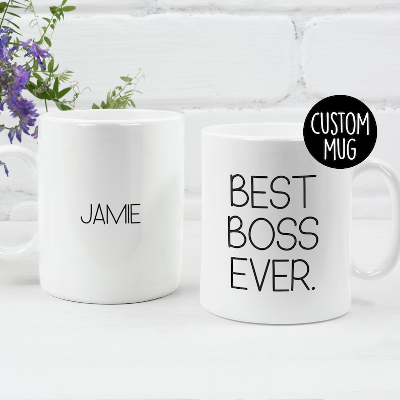 May include: Two white ceramic mugs. One mug has the text "BEST BOSS EVER." printed in black. The other mug has the name "JAMIE" printed in black.