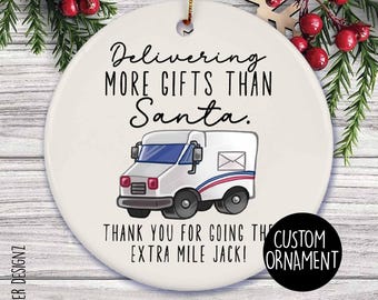 Op de afbeelding: Ronde, witte keramische kerstversiering met een illustratie van een postwagen. De tekst luidt: "Delivering MORE GIFTS THAN Santa." en "THANK YOU FOR GOING THE EXTRA MILE JACK!" Een feestelijke vakantiedecoratie.