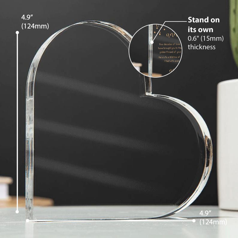 May include: A clear, heart-shaped acrylic keepsake, 4.9 inches (124mm) tall and wide, with a 0.6 inch (15mm) thickness. The transparent design allows light to pass through. Text is visible on the keepsake. It stands on its own.