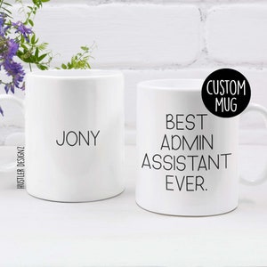 May include: Two white ceramic mugs. One mug has the name "Jony" printed on it. The other mug has the text "Best Admin Assistant Ever." printed on it. The mug with the text also has a black circle with the text "Custom Mug" printed on it.