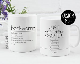 May include: Two white ceramic mugs with black text and illustrations. The mug on the left has the word "bookworm" and a definition. The mug on the right has the text "Just one more chapter..." and a drawing of a stack of books. The mug on the right also has the name "Jony" written below the books.