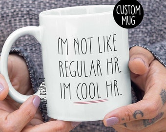 May include: White ceramic coffee mug with black text that reads "I'm not like regular HR. I'm cool HR." The text is underlined with a thin red line.