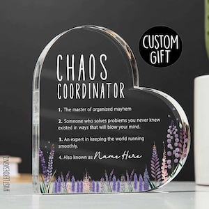 Puede incluir: Una placa acrílica transparente en forma de corazón con un diseño en blanco y negro que dice "Chaos Coordinator". La placa tiene un diseño floral con flores moradas y rosas. El texto dice: "1. El maestro del caos organizado. 2. Alguien que resuelve problemas que nunca supiste que existían de maneras que te dejarán boquiabierto. 3. Un experto en mantener el mundo funcionando sin problemas. 4. También conocido como: Nombre aquí."