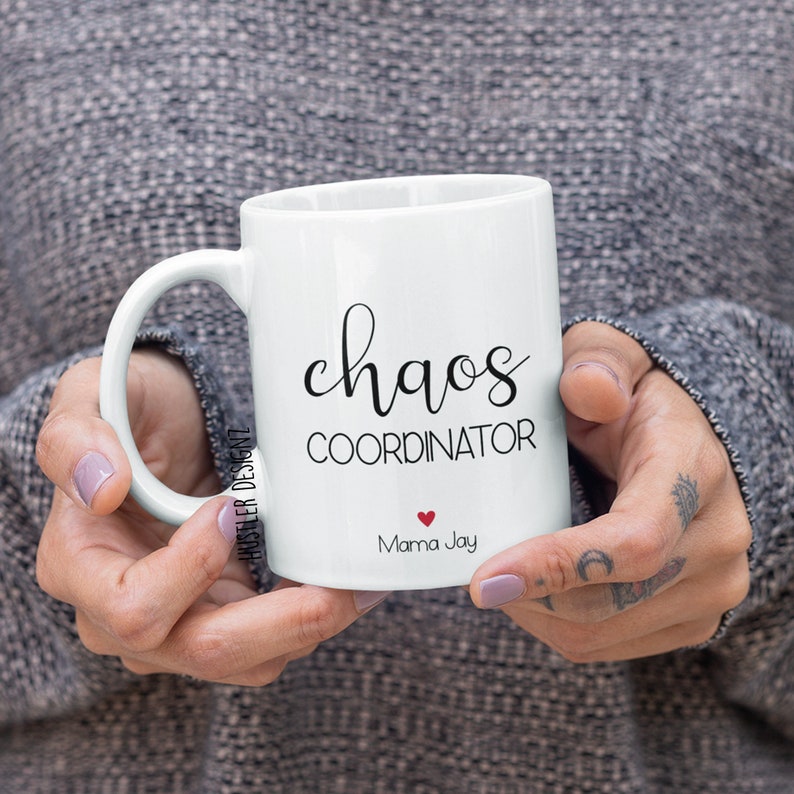 May include: White ceramic coffee mug with black text that reads "chaos coordinator" and "Mama Jay" with a small red heart.