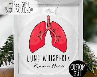 Puede incluir: Un adorno redondo blanco con una imagen de dibujos animados de pulmones rojos y el texto "Lung Whisperer Name Here Custom Gift".