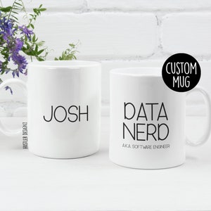Könnte beinhalten: Zwei weiße Keramikbecher mit schwarzem Text. Ein Becher sagt "Josh" und der andere Becher sagt "Data Nerd AKA Software Engineer".