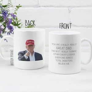 a white ceramic coffee mug with the text 'You are a really, really Great Dad. The best. Really terrific. Other dads? Losers! Everyone agrees. Total disasters. Believe me.' printed. on the other side there is an image of donald trump