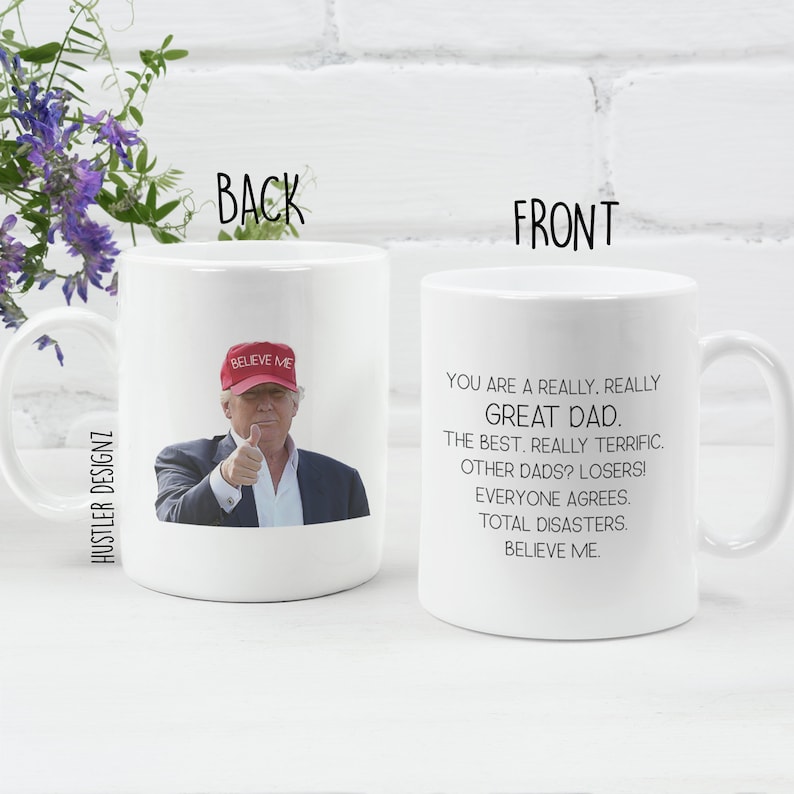 a white ceramic coffee mug with the text 'You are a really, really Great Dad. The best. Really terrific. Other dads? Losers! Everyone agrees. Total disasters. Believe me.' printed. on the other side there is an image of donald trump