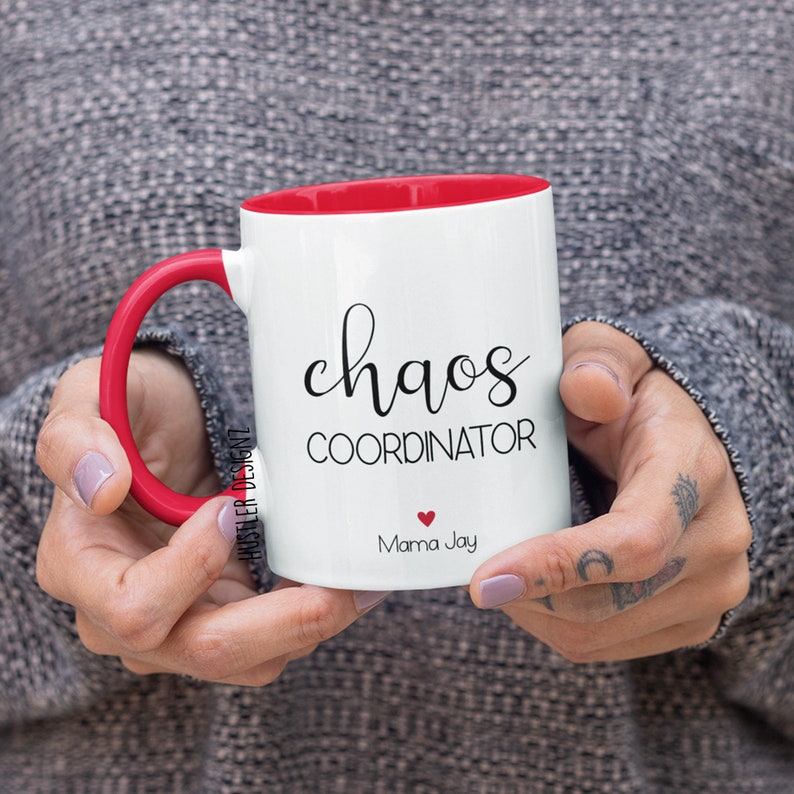 May include: White ceramic mug with a red rim and handle. The mug has black text that reads "chaos coordinator" and "Mama Jay" with a small red heart.