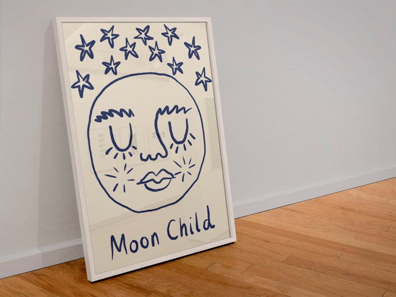 May include: A framed wall art print featuring a cream-colored background with a dark blue line drawing of a face with closed eyes and lips, surrounded by stars above the head, and the text Moon Child written in dark blue at the bottom.