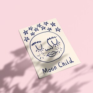 May include: A rectangular off-white card featuring a dark blue line drawing of a moon face with closed eyes, surrounded by stars above and small starbursts on the cheeks. The text "Moon Child" is written in dark blue ink at the bottom right.