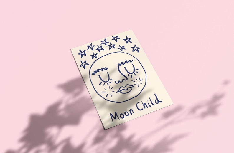 May include: A rectangular off-white card featuring a dark blue line drawing of a moon face with closed eyes, surrounded by stars above and small starbursts on the cheeks. The text "Moon Child" is written in dark blue ink at the bottom right.