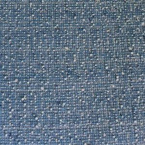 May include: Close-up of a textured blue fabric with white flecks. The fabric has a woven appearance and a slightly rough texture. The edges of the fabric are visible, showing the raw, unfinished edges.