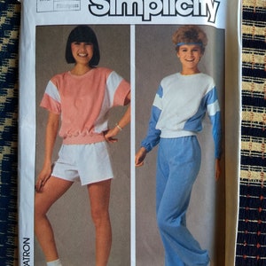 May include: Simplicity sewing pattern number 6906 for a women's top and trousers. The pattern includes instructions for using an overlock machine. The model on the left is wearing a pink and white top with white shorts. The model on the right is wearing a white and blue top with blue trousers.
