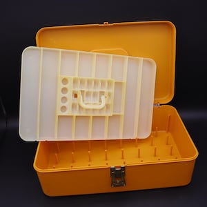 May include: A rectangular mustard yellow plastic storage box with a hinged lid and a metal latch. Inside, a removable cream-colored plastic tray features multiple rectangular compartments and a central handle for organizing small items.