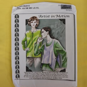 May include: A sewing pattern envelope titled Artist in Motion by The Cutting Line Designs, pattern #62612, featuring illustrations of two figures wearing green long-sleeved tunics and a light-colored over-vest, with text describing the garment design.