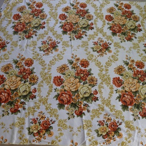 Puede incluir: Un mantel blanco con un patrón floral con rosas naranjas, amarillas y verdes. El mantel tiene un patrón repetitivo de ramos de flores.