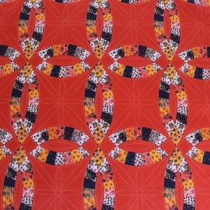 May include: A quilt featuring a repeating double wedding ring pattern with vibrant red fabric segments. The curved ring sections are pieced together from various small floral and geometric patterned fabrics in yellow, black, and white tones.
