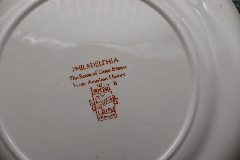 K&ouml;nnte beinhalten: Wei&szlig;er Teller mit braunem Text "PHILADELPHIA The Scene of Great Events In our American History" und dem Logo Imperial & Salem Chinaco.