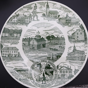 K&ouml;nnte beinhalten: Ein wei&szlig;er Keramikteller mit einer gr&uuml;nen Illustration von Wahrzeichen von Hagerstown, Maryland. Der Teller zeigt Geb&auml;ude, einen Soldaten, Flaggen und den Text "Hagerstown 200th Anniversary" und "Antietam South Mountain Centennial".