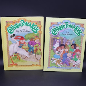 Könnte beinhalten: Ein Set aus drei Keramikbechern mit gesprenkelter, matter Oberfläche. Die Becher sind in Creme-, Hellgrau- und Dunkelgrautönen gehalten. Jeder Becher hat ein schlichtes, minimalistisches Design und einen abgerundeten Griff.