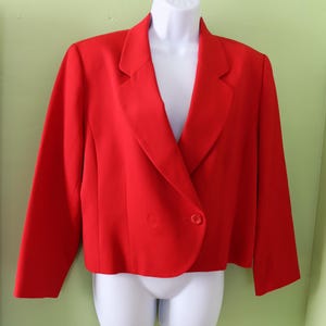 Op de afbeelding: Een rode blazer met een enkele knoopsluiting en een lange, puntige kraag.