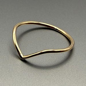 Può includere: Un semplice anello d'oro con un design curvo a forma di V.