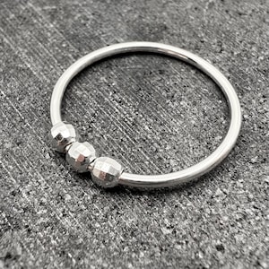 May include: A silver bangle bracelet with three textured silver beads.