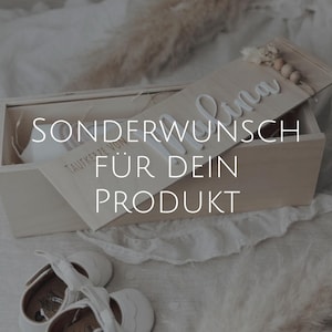 Könnte beinhalten: Eine hellfarbene Holzkiste mit dem Text "SONDERWUNSCH FÜR DEIN PRODUKT" in Weiß. Die Kiste ist geöffnet und zeigt einen weißen Gegenstand und einen Holzdeckel mit dem Namen "Lina" in Weiß. Weiße Babyschuhe sind im Vordergrund.