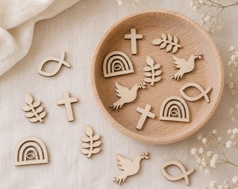 Peut inclure: Une collection de petites découpes en bois clair représentant des formes religieuses et inspirées de la nature, notamment des croix, des colombes, des arcs-en-ciel avec des poissons et des branches feuillues, disposées dans un bol en bois.