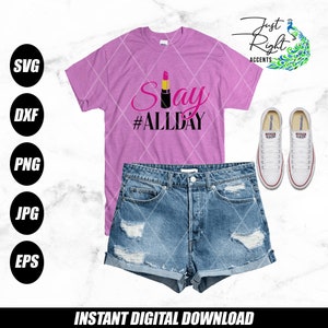 May include: A pink t-shirt with the text "Say #ALLDAY" in black and pink lettering. A red lipstick is featured in the design. The t-shirt is displayed on a model with denim shorts and white sneakers.