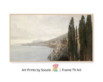 Op de afbeelding: Een ingelijste landschapsafdruk toont een kustlandschap met een stad aan een klif. Hoge, donkergroene bomen staan op de voorgrond. De lucht is bewolkt en de zee is een gedempt blauw. De tekst "Art Prints by Soozie | Frame TV Art" staat onderaan.