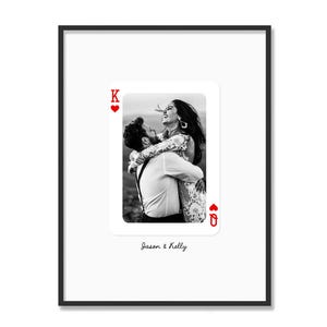 May include: Black framed print with a black and white photo of a couple embracing. The photo is in the shape of a playing card, with the King of Hearts and Queen of Hearts symbols. The names "Jason & Kelly" are written below the card.