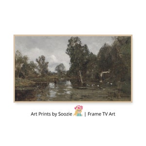 May include: A framed landscape painting depicts a tranquil river scene with trees and a cloudy sky. The artwork features muted tones of green, brown, and gray, creating a serene atmosphere. The text "Art Prints by Soozie | Frame TV Art" is visible at the bottom.