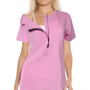 May include: A pink short-sleeved t-shirt with a zipper down the front. The zipper is open, revealing a white undershirt.