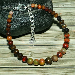 Peut inclure: Un bracelet en opale multicolores avec un fermoir argenté. Le bracelet présente un dégradé de couleurs allant du brun foncé au vert clair.