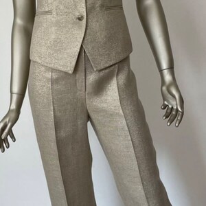 May include: A gold-colored pantsuit with a vest and pants. The fabric has a subtle shimmer.