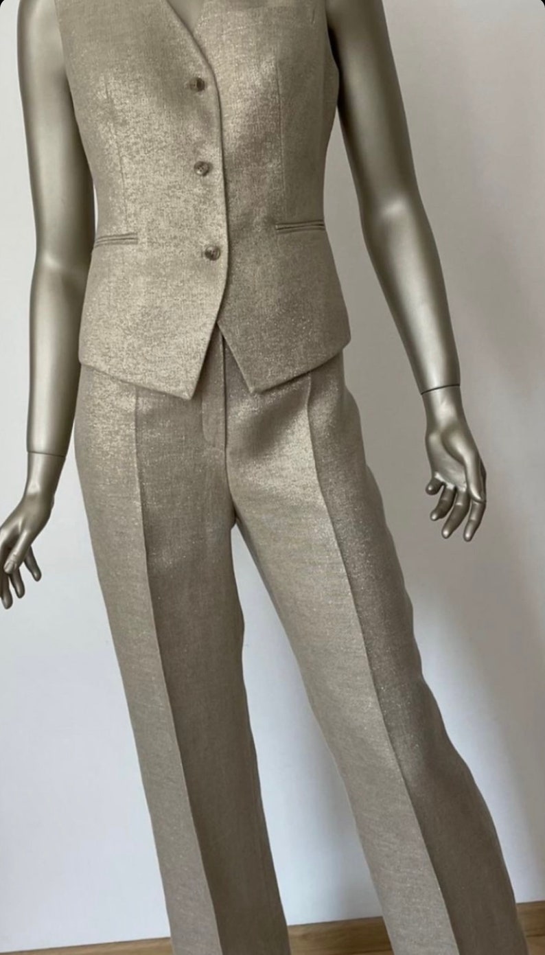 May include: A gold-colored pantsuit with a vest and pants. The fabric has a subtle shimmer.